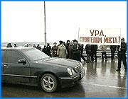 ></p><p class=c_tn>Свершилось! В минувшую субботу открыли так называемое рабочее движение по кинешемскому мосту через Волгу. Рабочее, потому что окончательно мост сдадут после того, когда построят очистные сооружения и заасфальтируют тридцать восемь километров дороги до Костромской губернии. Несмотря на недоделки, открытие моста сопровождалось грандиозным размахом и отсутствие нескольких приглашенных министров, настроение собравшимся не испортило. Топоры политических войн брошены в воду, -  недавние оппоненты плечом к плечу на свежесколоченной трибуне . Прорабы с просветленными лицами прощают друг другу недавние споры относительно завышенных смет и курят на одной площадке подъемного крана. Хмурое небо над Волгой разрезают зажженные по всему мосту новенькие фонари. Надо всем действом возвышается транспарант с известным лозунгом и до боли знакомыми символами. Встреча на Волге кажется всех объединила и всех примирила. Высокопоставленные гости и местные чиновники говорят о прошлом, настоящем и будущем, но смысл один  - рабочему движению по мостовому переходу через реку Волгу быть! Губернатор Тихонов вспоминает 98 год, крах российского дорожного фонда и ожесточенную борьбу , свою лично и сенатора Гусева, за сохранение этой структуры: «Мы взяли тогда на себя обязательство и сумели убедить думские фракции и комитеты проголосовать за сохранение фонда...»  </p><p class=c_tn>«Росавтодор» как бы в благодарность за этот благородный поступок финансирует строительство кинешемского моста»,  - ностальгирует глава области. «Это сооружение позволит вывести на более высокий уровень жизни по крайней мере заволжский район и даст импульс всей области», - продолжает Владимир Тихонов. «Да, мы знаем, что бедность преследует Ивановскую губернию, но теперь у вас есть спасительная соломинка - мост», - продолжает мысль губернатора представитель представителя Президента по ЦФО Николай Макаров</p><p class=c_tn>Многочисленные выступления, затем поздравления и награждение строителей,  - все это происходит под прицелом многочисленных теле и фотокамер. Кто-то еще хочет высказаться, но по сценарию уже пора освящать мост и  перерезать ленточку. «Дай нам разума и избавь нас от лукавого...», - вступают священнослужители.</p><p class=c_tn>Дорога в будущее,способ преодоления бедности, и даже сие великое творение, - кто-то выступает экспромтом, другие пользуются домашними заготовками. Впрочем, уже не важно кто и что говорил, и кто к какой относится партии. Ведь если вспомнить, то мост строили более десяти лет и никто не знает сколько денег на него потратили, и сколько политиков из-за него переругались. Теперь есть одна лишь правда - его построили!</p><p class=c_tn> На пронизывающем ветру девушки в летних сарафанах подают ножницы. Ленточку перерезают трое мужчин - двое в пальто, один в пуховике а-ля Путин. Руководитель «Росавтодора» Слюняев, директор «Ивавтодора» Васильев, губернатор Тихонов посередине, с ленточками в руках бодрым шагом идут на противоположную сторону моста. За ними двигается колонна строительных машин, непосредственно строителей, в хвосте служебный транспорт чиновников. Если бы не российские флаги на автомобилях, то действо очень сильно бы напоминало открытие БАМА. На той стороне заволжцы  встречают делегацию оптимистичными транспарантами..., залпами из сигнального пистолета...., частушками и песнями из категории как молоды мы были . Настроение приподнятое, заволжцы буквально пьяны...от счастья. </p><p class=c_tn>После недолгого осмотра бездорожья, которое надо асфальтировать, кортеж уносится обратно по новому мосту, поближе к столам в одном из ивановских ресторанов. Кто-то из сопровождения роняет фразу - торопятся, надо успеть на футбол «Россия –Уэльс». А кто-то только спешит на праздник и понимает, что уже безнадежно опаздывает и что движение по мосту действительно пока еще только рабочее.  </p><p class=c_av>Андрей Кузьмичев</p>
	
		<div class=